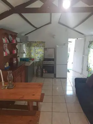 a kitchen with a table and a refrigerator at Chalet 1 Camping Style at Cynthias Country Farmstay Outside bathroom in Hartbeespoort