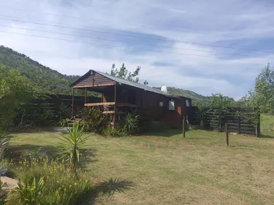 a wooden cabin in a field with a fence at Chalet 1 Camping Style at Cynthias Country Farmstay Outside bathroom in Hartbeespoort