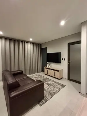 a living room with a leather couch and a flat screen tv at King size bed-NO loadshedding-Free Wi-Fi in Pretoria