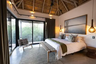 a bedroom with a large bed and a large window at Villa Visvanger - Villa with river deck nearby Kruger in Hoedspruit