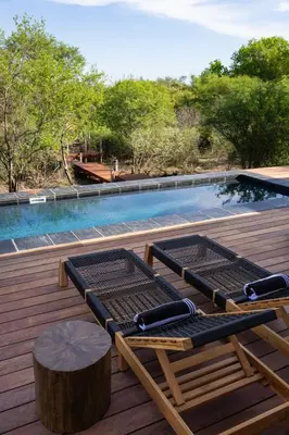a deck with two lounge chairs and a swimming pool at Villa Visvanger - Villa with river deck nearby Kruger in Hoedspruit