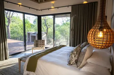 a bedroom with a large bed and a large window at Villa Visvanger - Villa with river deck nearby Kruger in Hoedspruit