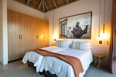 a bedroom with a large bed and a painting on the wall at Villa Visvanger - Villa with river deck nearby Kruger in Hoedspruit