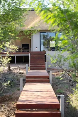 a wooden path leading up to a house with trees at Villa Visvanger - Villa with river deck nearby Kruger in Hoedspruit