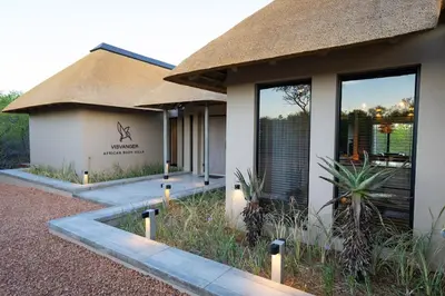 a building with a thatched roof and some plants at Villa Visvanger - Villa with river deck nearby Kruger in Hoedspruit