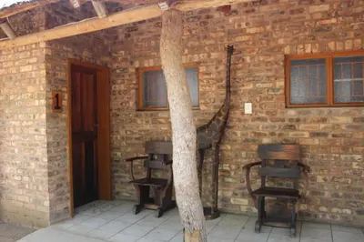 a room with a brick wall with chairs and a tree at Corea Game Ranch in Alldays