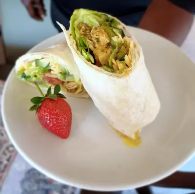 a burrito and a strawberry on a white plate at Corea Game Ranch in Alldays