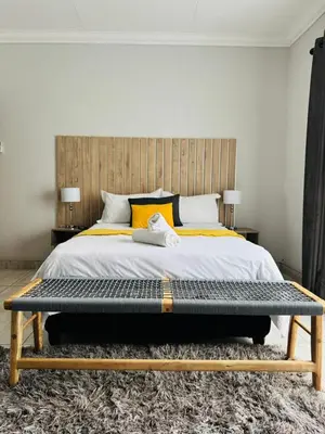 a bedroom with a large bed with a wooden headboard at Kioma Guest House in Mokopane