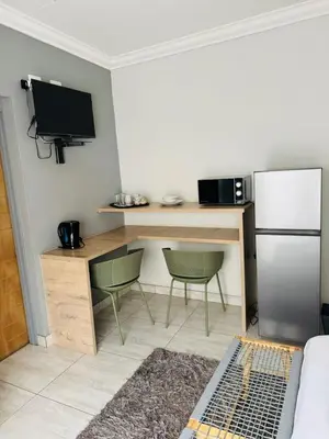 a kitchen with a desk and a refrigerator and two chairs at Kioma Guest House in Mokopane