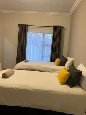 a bedroom with two beds with yellow pillows and a window at Kioma Guest House in Mokopane