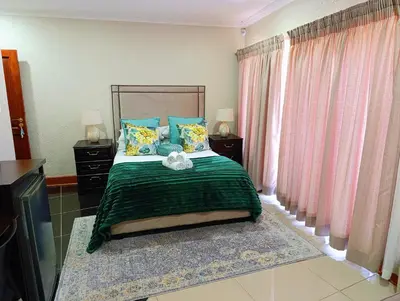 a bedroom with a bed with a green blanket at Elephant Villa Private Room in Nelspruit