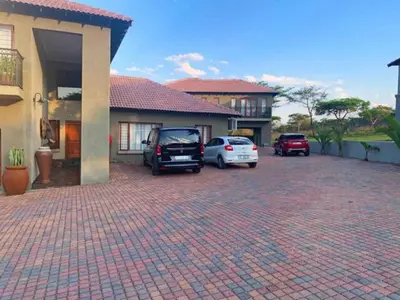 a parking lot with cars parked in front of a house at Elephant Villa Private Room in Nelspruit