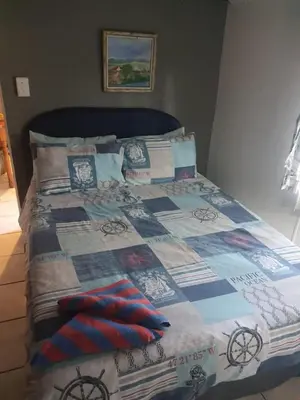 a bed with a quilt and pillows on it at Chalet 2 Camping Style at Cynthias Country Outside bathrooms in Hartbeespoort