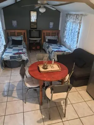 a living room with a table and chairs and a couch at Chalet 2 Camping Style at Cynthias Country Outside bathrooms in Hartbeespoort
