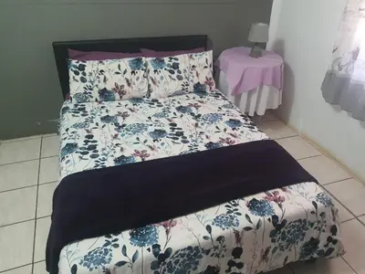 a bed with a floral comforter and two pillows at Chalet 3 at Cynthias Country in Hartbeespoort