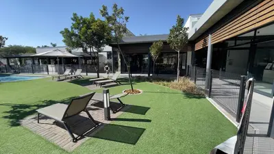 a group of chairs sitting on the grass next to a building at Ruby Nest Modern Smart Living in Midrand