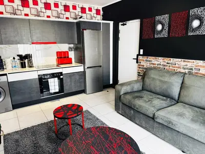 a living room with a couch and a kitchen at Ruby Nest Modern Smart Living in Midrand