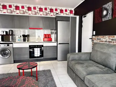a living room with a couch and a kitchen at Ruby Nest Modern Smart Living in Midrand