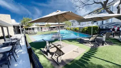 a pool with tables and chairs and an umbrella at Ruby Nest Modern Smart Living in Midrand