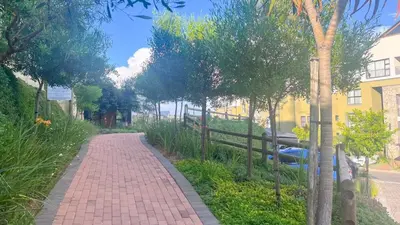 a brick path with trees and a yellow building at Smart Home Oasis & Luxury Living in Midrand