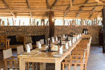 a long wooden table in a room with chairs at Honeyguide Ranger Camp in Golders Green