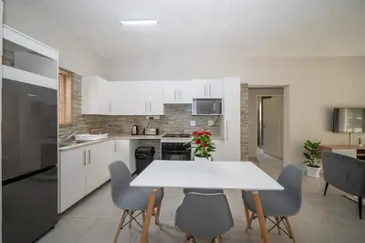 a kitchen with a white table and chairs in a kitchen at Self checkin - Modern 2 Bedroom Retreat - 103 in Nelspruit