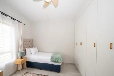 a small bedroom with a bed and a window at Self checkin - Modern 2 Bedroom Retreat - 103 in Nelspruit
