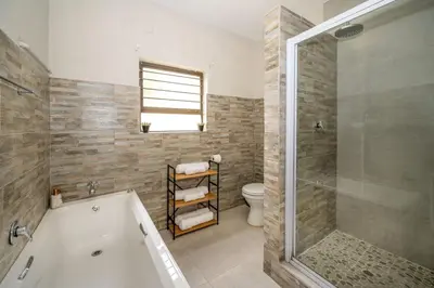a bathroom with a tub and a toilet and a shower at Self checkin - Modern 2 Bedroom Retreat - 103 in Nelspruit