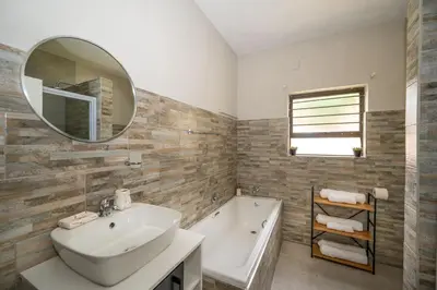 a bathroom with a sink and a tub and a mirror at Self checkin - Modern 2 Bedroom Retreat - 103 in Nelspruit