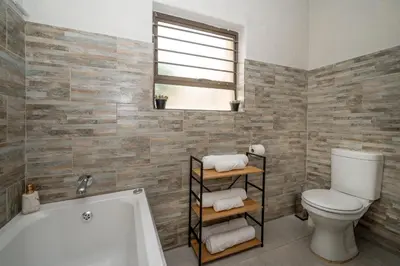 a bathroom with a toilet and a bath tub at Self checkin - Modern 2 Bedroom Retreat - 103 in Nelspruit