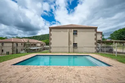 a swimming pool in front of a house at Self checkin - Modern 2 Bedroom Retreat - 103 in Nelspruit