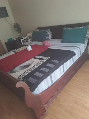 a large bed with a wooden frame in a room at Matte guest house in Secunda in Secunda