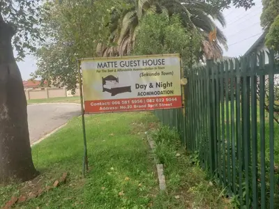 a sign for aknife guest house next to a fence at Matte guest house in Secunda in Secunda