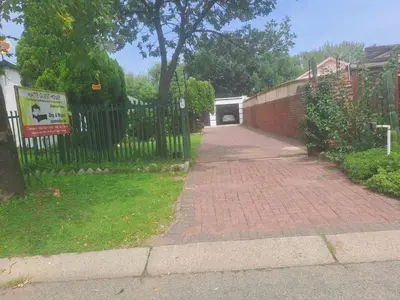 a brick driveway with a black fence and a garage at Matte guest house in Secunda in Secunda
