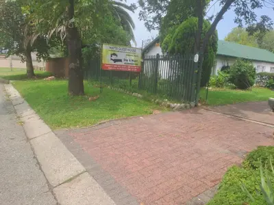 a sign on a fence next to a brick driveway at Matte guest house in Secunda in Secunda