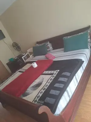 a bed with a wooden frame with a red blanket on it at Matte guest house in Secunda in Secunda