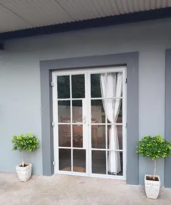 a sliding glass door with two potted plants next to it at Kaldi Kothuis in Marble Hall