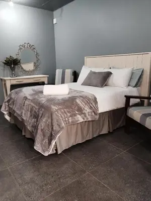 a bedroom with a large bed and a mirror at Kaldi Kothuis in Marble Hall