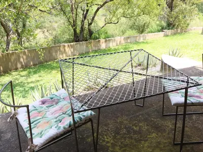 a bird cage sitting on a table with two chairs at Meulensrus in Hoedspruit