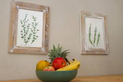 a bowl of fruit on a table with two paintings at Meulensrus in Hoedspruit