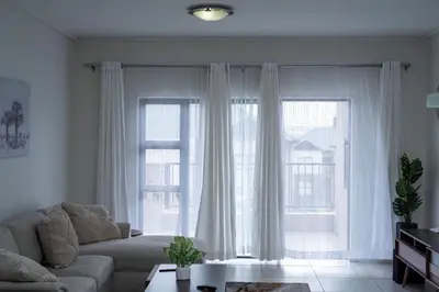 a living room with a couch and two large windows at Feelathome in Midrand