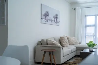 a white living room with a couch and a table at Feelathome in Midrand