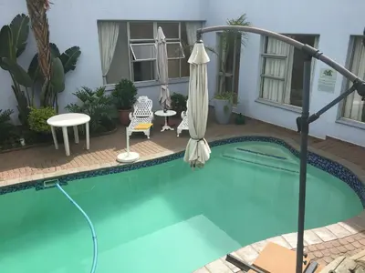 a swimming pool with an umbrella and a table and chairs at Isle La Breeze Guest House in Witbank