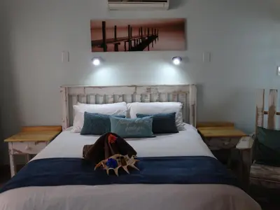 a bedroom with a large bed with a wooden headboard at Isle La Breeze Guest House in Witbank
