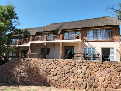 a house behind a stone wall at Kulanka Lodge in Roodeplaat
