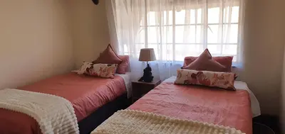 a bedroom with two beds and a window at Kulanka Lodge in Roodeplaat