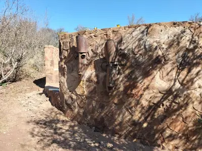 two masks on a stone wall on a dirt road at Kulanka Lodge in Roodeplaat