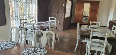 a dining room with white chairs and a table at Kulanka Lodge in Roodeplaat
