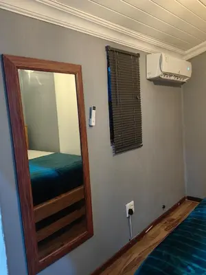 a mirror in a room with a bed and a window at The Cozy Cabin in Pretoria