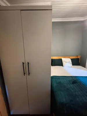a bedroom with a bed and a cupboard at The Cozy Cabin in Pretoria
